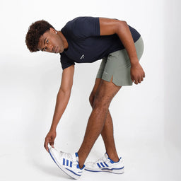 Short VISTORR verde militar em movimento, modelo flexionando perna, detalhe da fenda.