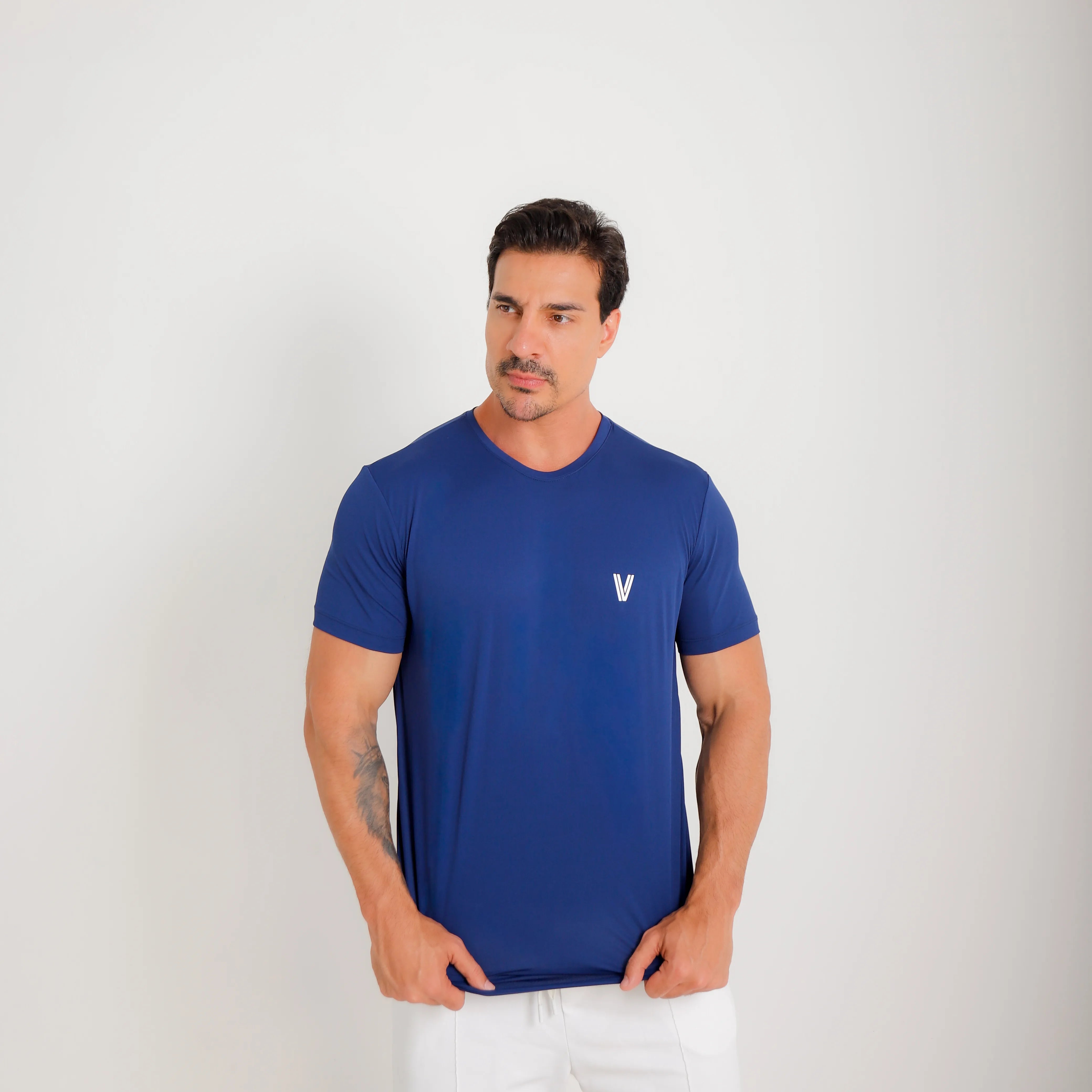 Camiseta de poliamida azul — logo Vistorr no peito — mãos soltas, olhar à esquerda, logo legível