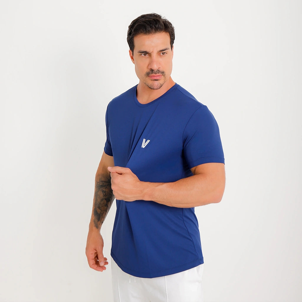 Camisetas Poliamida Esportiva azul-marinho em ângulo 3/4; mão na barra destacando caimento leve e elasticidade.