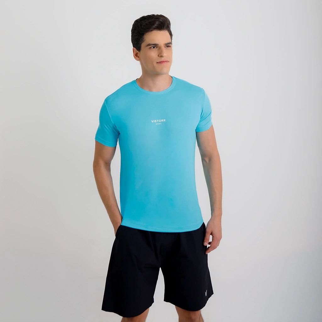 Modelo sorrindo em ângulo usando Camisetas Poliamida UV30 azul claro e short preto.