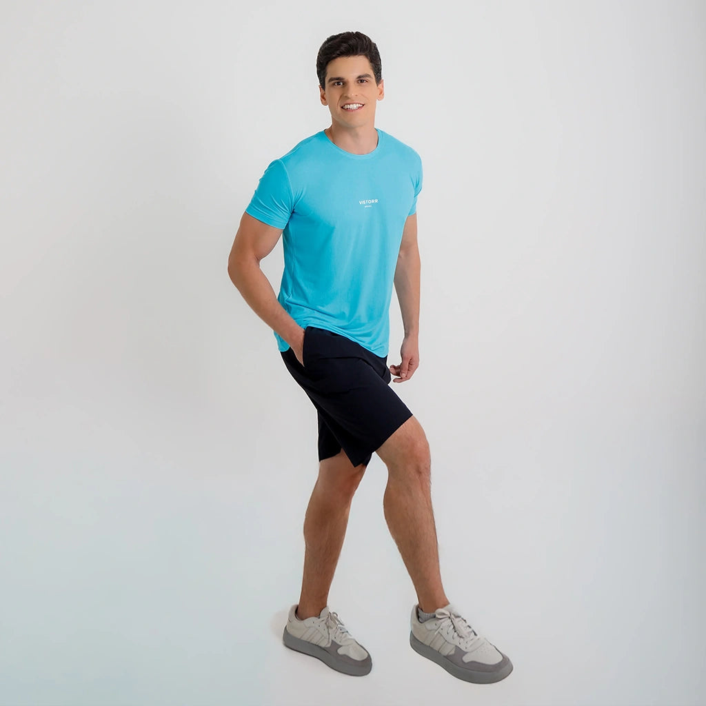 Modelo em posição de caminhada usando Camisetas Poliamida UV30 azul claro, short preto e tênis claros.