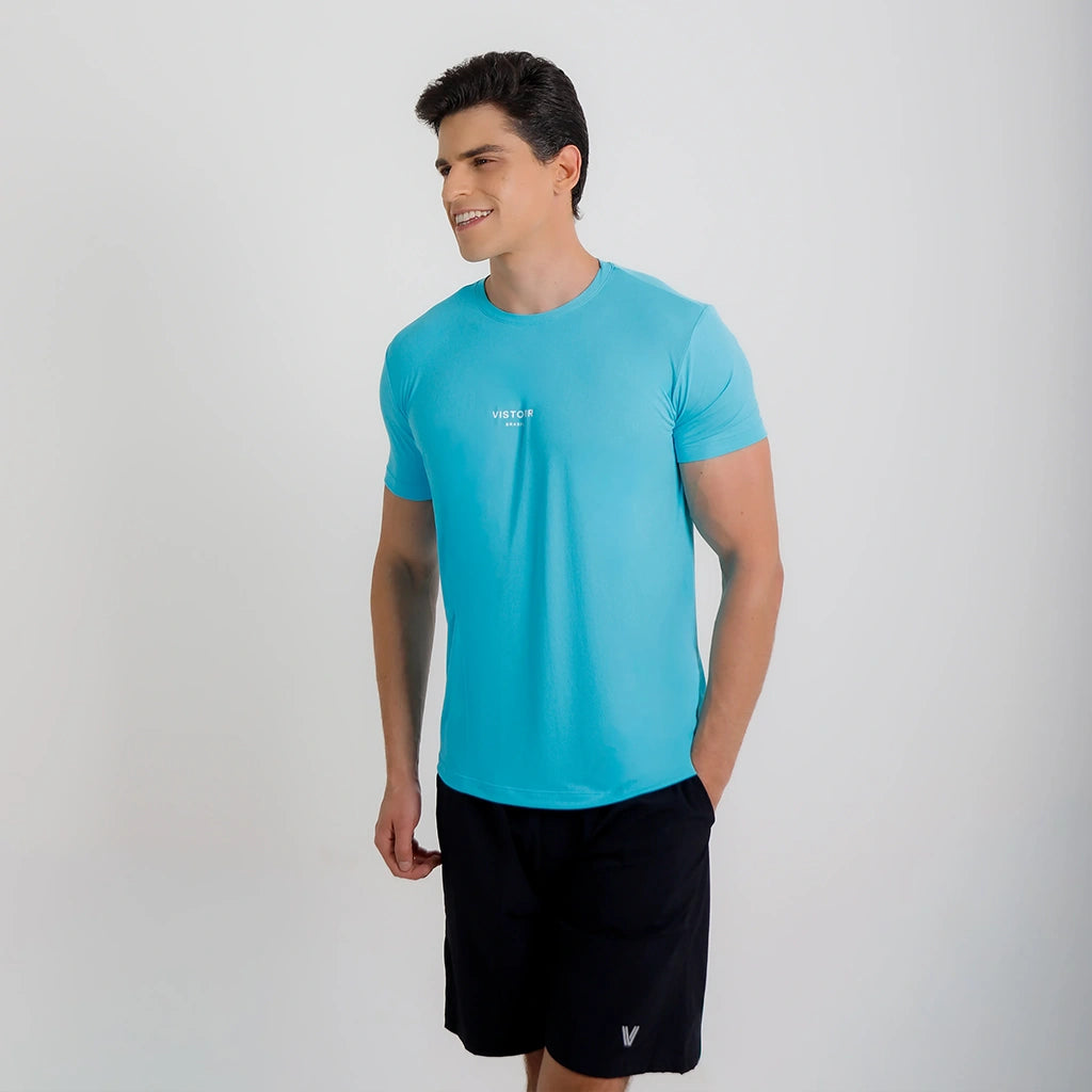 Modelo sorrindo em ângulo usando Camisetas Poliamida UV30 azul claro e short preto.