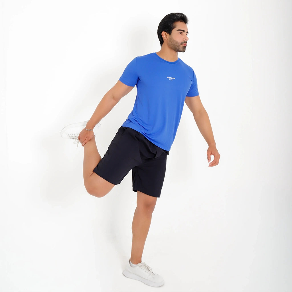 Modelo alongando a perna usando Camisetas Poliamida UV30 azul e short preto.