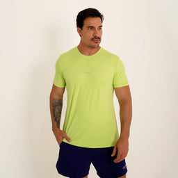 Modelo em ângulo usando Camisetas Poliamida UV30 verde claro em fundo branco, com mão no bolso.