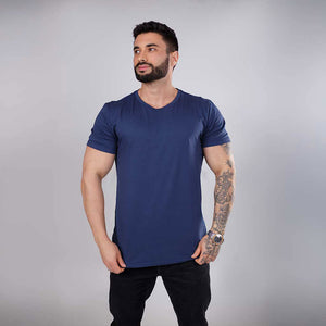 Homem tatuado de ângulo frontal vestindo camiseta azul.