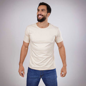 Homem sorrindo de frente vestindo camiseta bege de algodão.