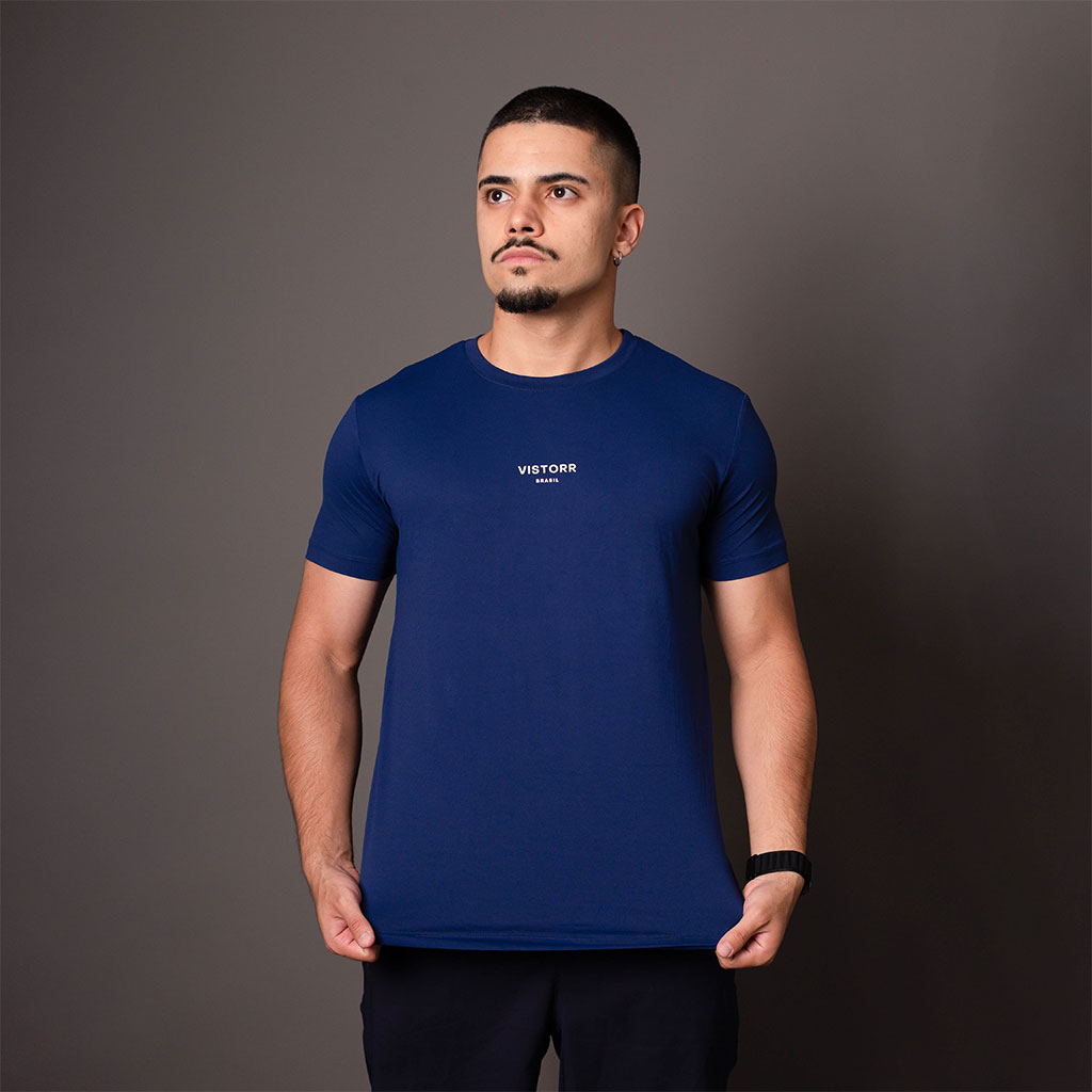 Modelo vestindo camiseta poliamida masculina azul Vistorr com logo centralizado no peito, em pose frontal.
