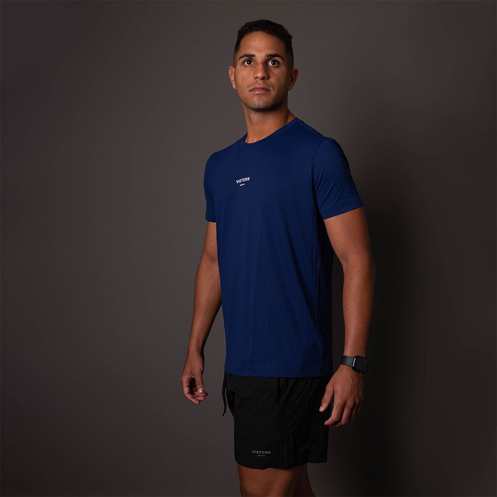 Modelo usando a camiseta de poliamida azul masculina Vistorr com logo no alto das costas. 