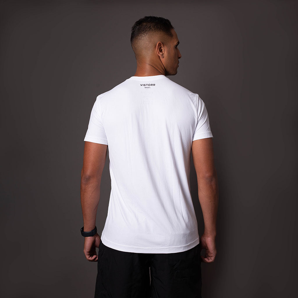 Modelo de costas usando camiseta branca em poliamida Vistorr masculina com logo discreto, ideal para treino ou casual. 