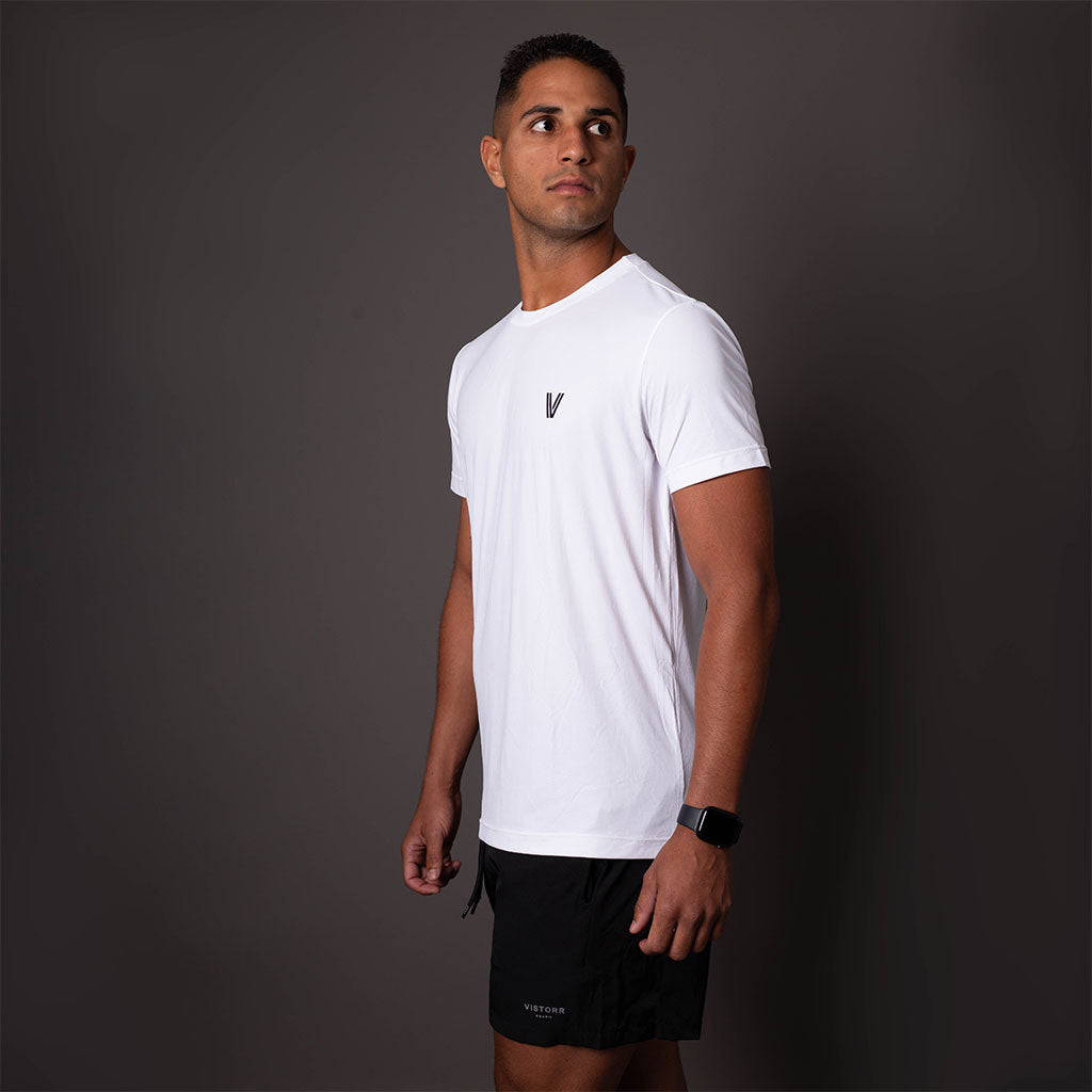 Modelo de lado usando camiseta branca em poliamida Vistorr masculina com logo discreto, ideal para treino ou casual. 