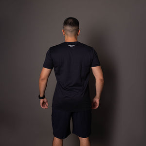 Modelo de costas usando a camiseta masculina preta em poliamida Vistorr com estampa discreta do logo no alto. 