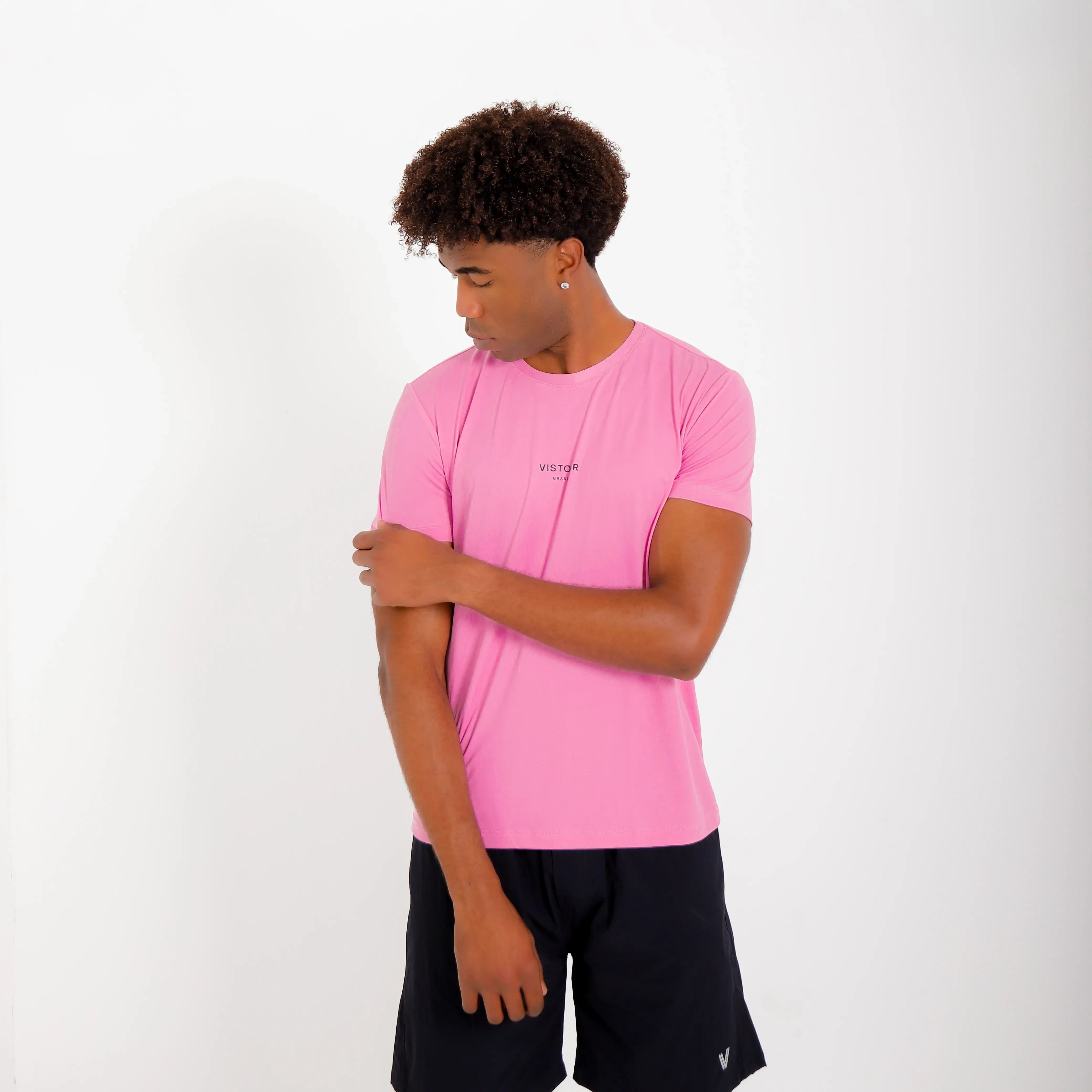 Camiseta de poliamida rosa — logo Vistorr Brasil — mãos soltas, olhar à esquerda, logo legível