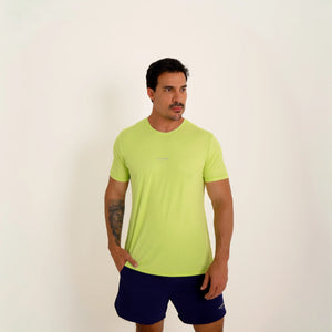Camiseta de poliamida verde — logo Vistorr Brasil — mãos soltas, olhar à esquerda, logo legível